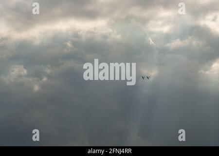 Farbbild von zwei Spitfire-Flugzeugen in Formation hoch in Den Himmel und in einem Strahl des Sonnenlichts gegen gehalten Viel dunklere Wolken Stockfoto