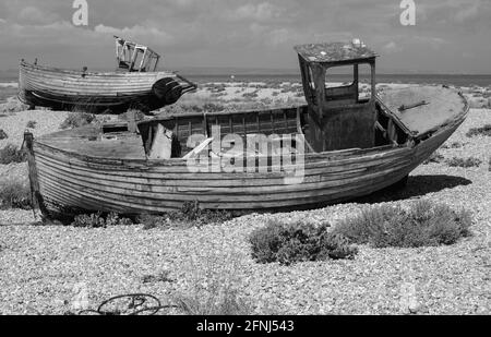 Monobild von zwei verfallenen, verlassenen und verfaulenden Fischerbooten an einem Kiesstrand Stockfoto