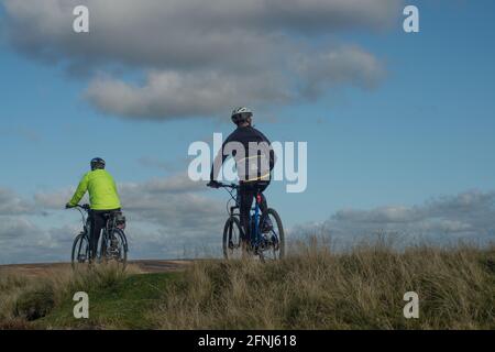 Zwei Radfahrer kommen vorbei und halten inne, um die umliegende Landschaft in den Durham Dales zu betrachten Stockfoto