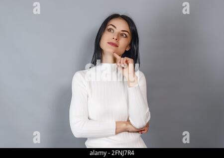 Hübsche Frau in einem weißen Pullover schaut auf die Kamera. Porträt einer erfolgreichen Geschäftsfrau Stockfoto