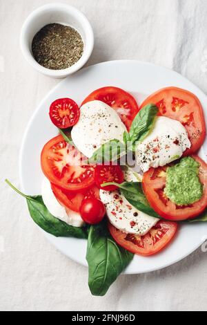 Caprese Salat. Tomaten, Mozzarella-Käse, Basilikumblätter und Pesto-Sauce. Stockfoto