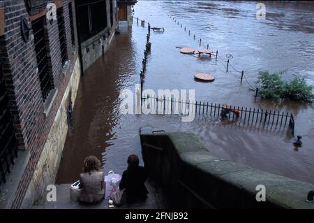 Paar sitzend auf Stufen und schauten auf den überfluteten Fluss Ouse in York, Yorkshire und The Humber, England, Großbritannien Stockfoto