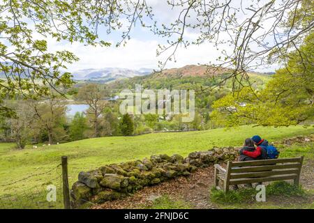 Sitzendes Paar auf einer Holzbank mit Blick auf Ambleside und den Lake windermere im Seengebiet. Stockfoto