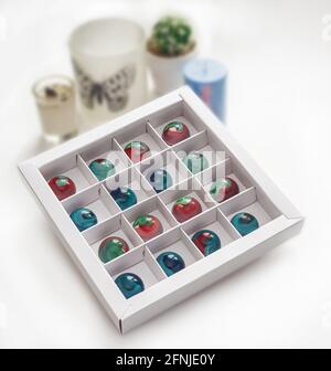 Gehärtete Schokolade Bonbons mit glänzend lackiertem Körper in einer Box mit verschwommenem Hintergrund und Bokeh-Elemente. Stock-Fotografie. Stockfoto