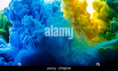 Gelbe, blaue und grüne Tinte im Wasser. Tintentropfen in Wasser. Abstrakter Hintergrund. Stockfoto