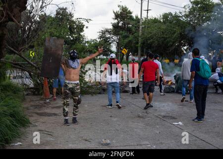 Demonstranten werfen Steine und entlarvten eine improvisierte Barrikade, als Demonstranten und die Polizei von Cali (ESMAD) nach dem Tod eines Demonstranten in der Nacht zuvor zusammenpriesen. Die Unruhen und Demonstrationen fanden mehrere Tage lang während der Anti-Regierungsproteste gegen den Präsidenten Ivan Duque, Steuer- und Gesundheitsreform, am 29. April 2021, in Yumbo, Valle del Cauca, Kolumbien, statt Stockfoto