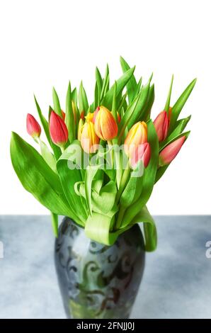 Tulpen mit Blättern in einer Vase auf weißem, selektivem Fokus. Stockfoto