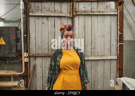 Porträt einer afrikanischen Frau in gelbem Kleid, die die Kamera anschaut Während Sie draußen auf dem Land stehen Stockfoto