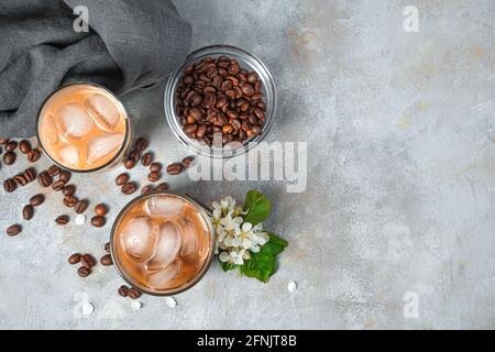 Eiskaffee und Kaffeebohnen auf grauem Hintergrund. Draufsicht, Kopierbereich. Stockfoto