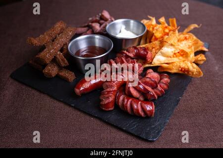 Stellen Sie einen Snack zu Bier aus Würsten, Crackern, Pommes Frites und geräuchertem Fleisch ein. Stockfoto