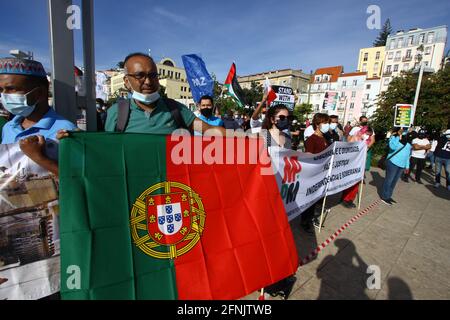 Lissabon, Portugal. Mai 2021. Ein Demonstranten trägt eine portugiesische Flagge während einer Kundgebung in Lissabon gegen israelische Einmischung. Die Kundgebung für „Solidarität mit Palästina“ fand auf dem Martim Moniz-Platz in der portugiesischen Hauptstadt statt und wurde vom portugiesischen Rat für Frieden und Zusammenarbeit (CPPC) organisiert. Die Bewegung für die Rechte des palästinensischen Volkes und für den Frieden im Nahen Osten (MPPM) und der Allgemeine Verband der portugiesischen Arbeitnehmer - Nationale Gewerkschaft (CGTP-IN). Kredit: SOPA Images Limited/Alamy Live Nachrichten Stockfoto