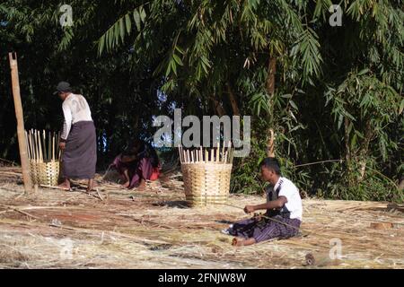 Shan State, Myanmar - Januar 7 2020: Einige burmesische Männer in longyi arbeiten an einem heißen, sonnigen Tag in einem ländlichen Dorf an Bambuskörben Stockfoto