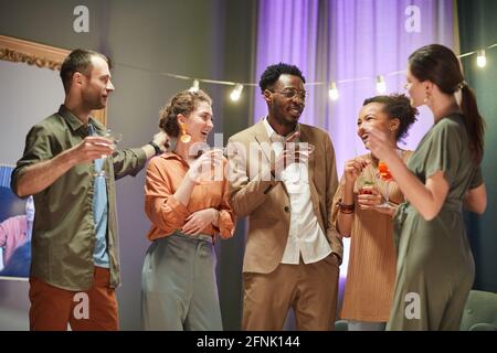 Waist-up-Porträt einer Gruppe von Freunden, die Spaß haben Und Cocktails zu Hause Party trinken Stockfoto