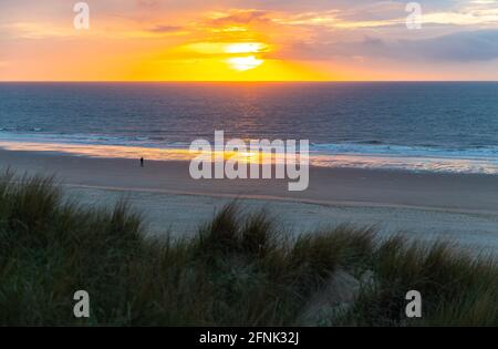 Silhouette eines Mannes, der den Sonnenuntergang am Nordseestrand von Oostende (Ostende) von Sanddünen aus gesehen, Westflandern, Belgien, betrachtet. Stockfoto