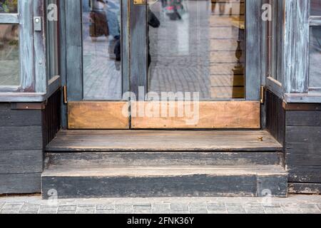 Türtreppe am Eingang zu einem alten Restaurant mit Eine Holzfassade und Glasfenster mit einer abgenutzten Schwelle Alte europäische Architektur aus nächster Nähe Stockfoto