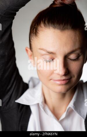 Eine junge Frau mit einem leichten Lächeln und geschlossenen Augen Trägt einen weißen shir Stockfoto