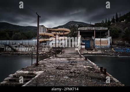 Heruntergekommener Blick auf den Freizeitpark vom Pier aus, mit Bergen im Hintergrund Stockfoto