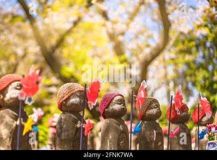 tokio, japan - 09 2021. april: Nahaufnahme von tausend Statuen des Kosodate Jizo Bodhisattva Beschützers der Kinder, dargestellt mit Strickmütze und Nadelrädern Stockfoto