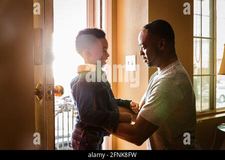 Seitenansicht eines lächelnden Sohnes mit Vater am Eingang von Zu Hause Stockfoto