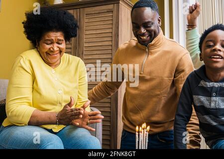 Glückliche, generationenübergreifende Familie, die zu Hause gemeinsam Geburtstag feiert Stockfoto