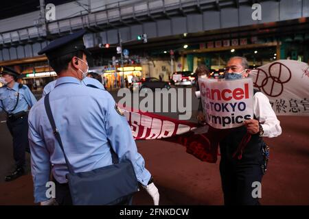 Tokio, Japan. Mai 2021. Ein Protestler hält ein Schild mit der Aufschrift: "Die Olympischen Spiele in Tokio abbrechen" vor einem Polizisten während einer gegen Tokio gerichteten Olympischen Spiele-Kundgebung 2020 im Stadtteil Ginza.rund 30 bis 40 Demonstranten gingen auf die Straße und forderten die Absage der Olympischen Spiele in diesem Sommer. Sie wurden von der gleichen Anzahl von Polizisten begleitet. Die Demonstranten gingen vom Bahnhof Shinbashi durch den Bezirk Ginza zum Hauptbüro des Organisationskomitees für die Spiele. Kredit: SOPA Images Limited/Alamy Live Nachrichten Stockfoto