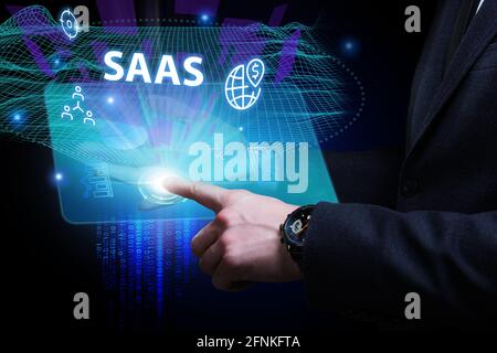 Business, Technologie, Internet und Netzwerkkonzept. Junger Geschäftsmann arbeitet auf einem virtuellen Bildschirm der Zukunft und sieht die Inschrift: SAAS Stockfoto