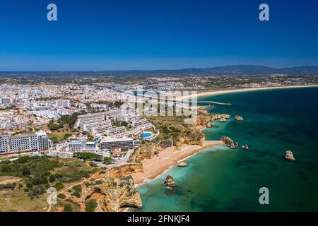 Dona Ana Strand in Lagos, Algarve - Portugal. Portugiesische südliche goldene Küstenklippen. Luftaufnahme mit der Stadt im Hintergrund. Camilo und pinhao Beach Stockfoto