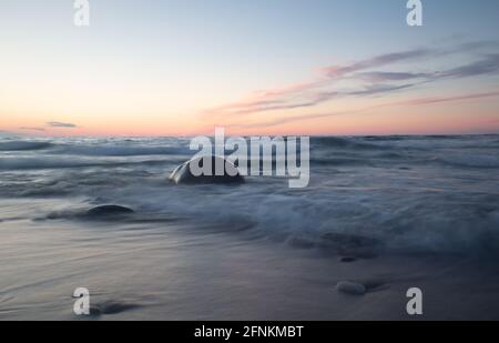 Wunderschöner Sonnenuntergang am Meer mit Felsen und Wellen Stockfoto
