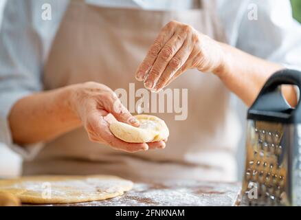 Nahaufnahme des Bäckers funktioniert. Hausgemachtes Brot. Hände, die Teig auf Holztisch vorbereiten. Stockfoto