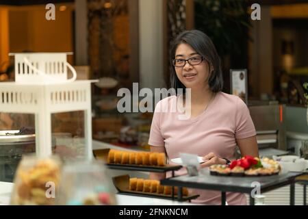 Portrait Asiatische Frau, die Essen in der Food Bar auswählt, Frühstücksbuffet in einem Restaurant. Stockfoto