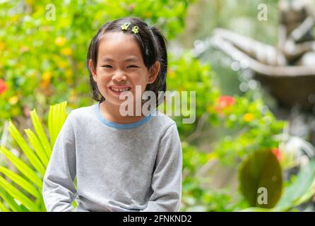 Süßes kleines Kind, das im Garten sitzt, Porträt eines asiatischen kleinen Mädchens. Stockfoto
