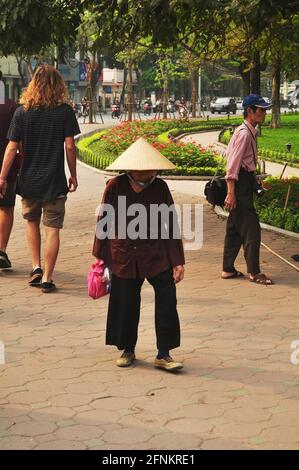 Vietnamesische alte Frauen gehen auf einem Fußgängerweg neben Hoan Kiem Teichgarten oder Lake of the Returned Sword Öffentlichkeit park gehen Sie zu Hoan Kiem Squa Stockfoto