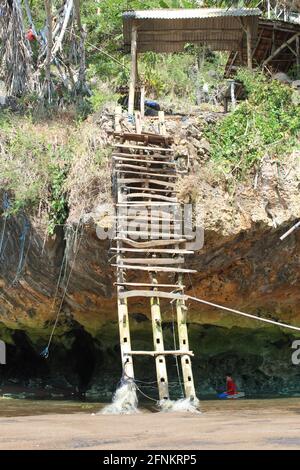 Kaputte Holztreppen auf einer felsigen Klippe am Strand Stockfoto
