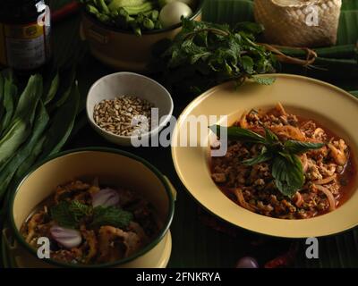 Nahaufnahme der traditionellen thailändischen Küche, würziger Schweinesalat (Larb Moo) mit klebrigem Reis, Gemüse und Zutaten Stockfoto