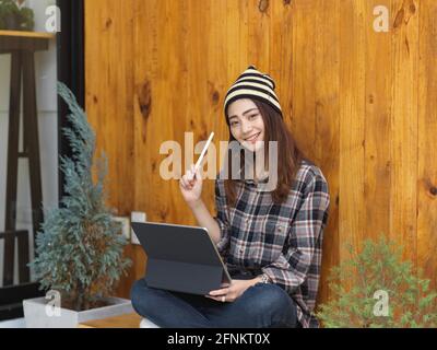 Porträt eines weiblichen Teenagers gekreuzte Beine sitzen in Café und Mit einem digitalen Tablet auf dem Schoß Stockfoto