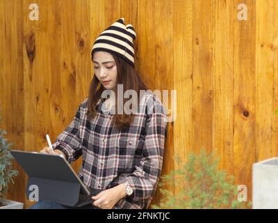 Porträt einer Teenagerin, die mit einem digitalen Tablet auf ihr arbeitet Runde, während Sie im Café sitzen Stockfoto