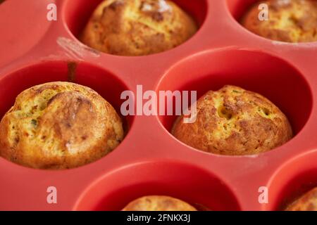 Gebackene Muffins mit sonnengetrockneten Tomaten in Silikonform nach dem Backen. Stockfoto