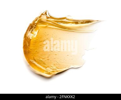 Transparenter gelber Abstrich von Gesichtscreme oder goldenem Honig isoliert auf weißem Hintergrund. Goldene cremige Textur auf weißem Hintergrund. Stockfoto