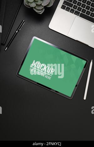 Draufsicht auf den schwarzen Tisch mit Tablet, Laptop, Büromaterial und Kopieplatz, einschließlich Beschneidungspfad Stockfoto