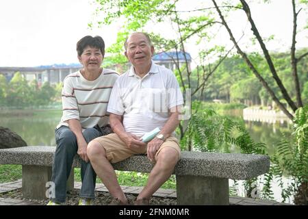 Glücklich lächelndes älteres asiatisches Paar im Park. Lifestyle nach dem Ruhestand Konzept. Stockfoto