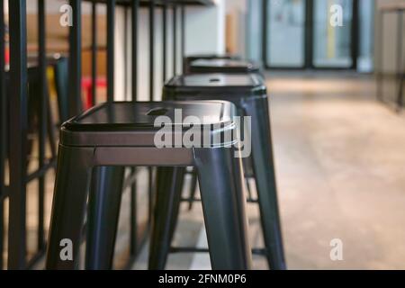 Nahaufnahme von schwarzen Metallhockern in einem leeren Restaurant. Stockfoto