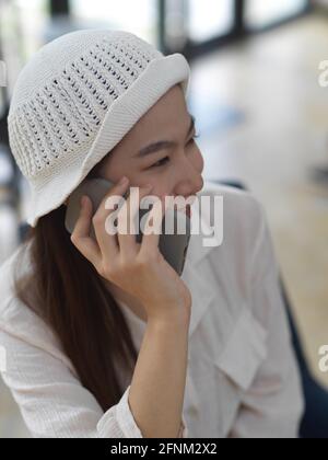 Porträt eines weiblichen Teenagers, der lächelt und am Telefon spricht Beim Sitzen im Café Stockfoto