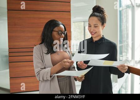 Zwei Geschäftsfrauen, die mit Dokumenten arbeiten und gleichzeitig Verträge diskutieren Arbeiten im Büro Stockfoto