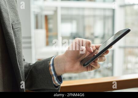 Nahaufnahme eines Geschäftsmannes, der eine Nachricht auf dem Mobiltelefon im Stehen eintippt Im Freien Stockfoto