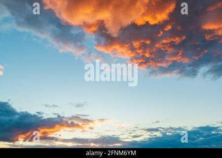 Epische Wolken am Sonnenuntergang. Dramatische orangefarbene Wolken, die von der Sonne beleuchtet werden. Hochauflösender Naturhintergrund Stockfoto