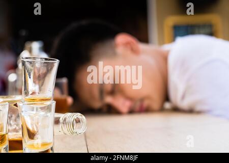 Kater schlafender Mann hinter den leeren Gläsern und Flasche an Tabelle Stockfoto