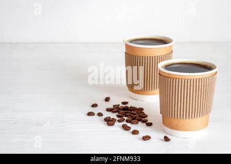 Schwarzer Kaffee in Pappbechern mit Bohnen. Nehmen Sie Kaffee Hintergrund Stockfoto