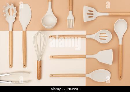 Muster aus Kochgeschirr-Set. Küchengeräte aus Silikon mit Holzgriff auf beigem Hintergrund. Draufsicht Flat Lay. Stockfoto