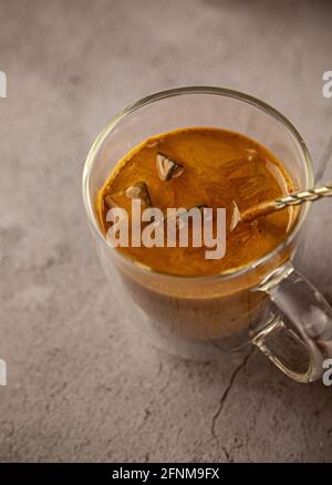 Iced Dalgona Kaffee Getränk auf Holz Tablett Hintergrund. Instant-Kaffee oder Espresso-Pulver mit Zucker und heißem Wasser geschlagen. Kaffee mit Milchlake Stockfoto