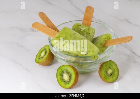 Gefrorener Obst-Kiwi-Saft in einer Schüssel. Erfrischender Popsicle auf einem Stock. Stockfoto